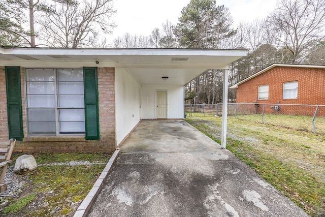 view of car parking with driveway, fence, and an attached carport