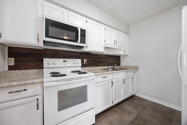 kitchen featuring white cabinetry, a sink, light stone countertops, white appliances, and baseboards