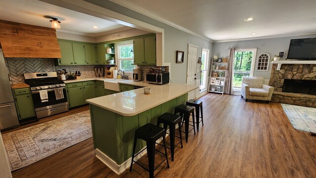 4232 Almond Rd, Fortson, GA 31808 - kitchen featuring green cabinetry, appliances with stainless steel finishes, a peninsula, dark wood finished floors, and a kitchen bar