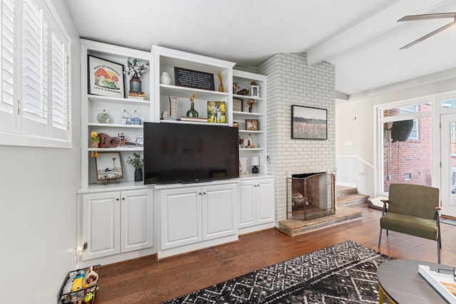 living room with vaulted ceiling with beams, a brick fireplace, dark wood finished floors, and a ceiling fan