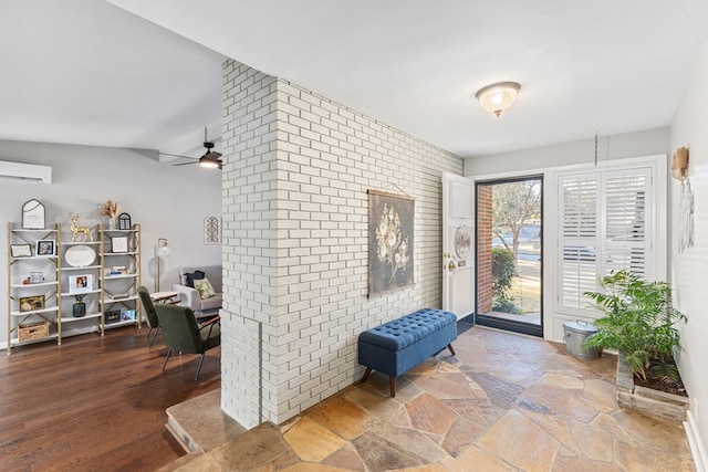 entryway with stone finish flooring, a wall mounted air conditioner, ceiling fan, and brick wall