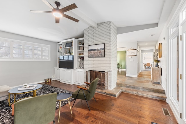 living room featuring visible vents, baseboards, vaulted ceiling with beams, light wood-type flooring, and a brick fireplace