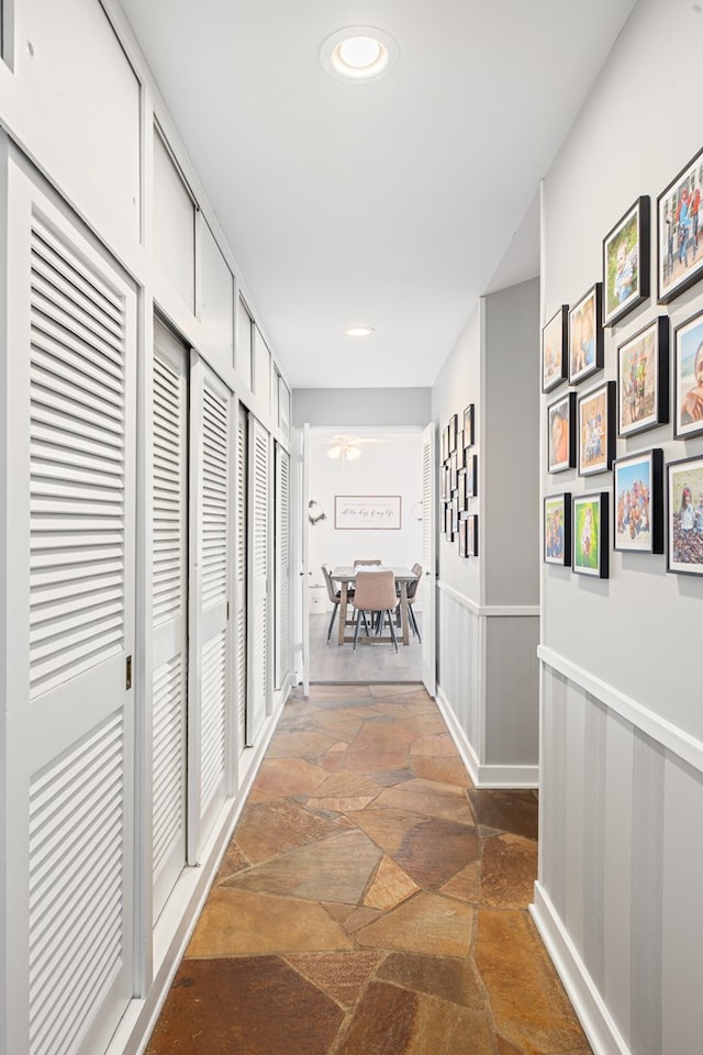 corridor with a wainscoted wall and stone tile floors