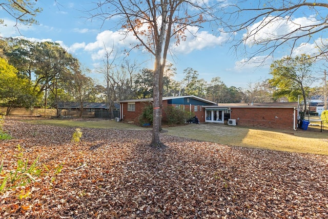 rear view of house with brick siding, fence, and a lawn