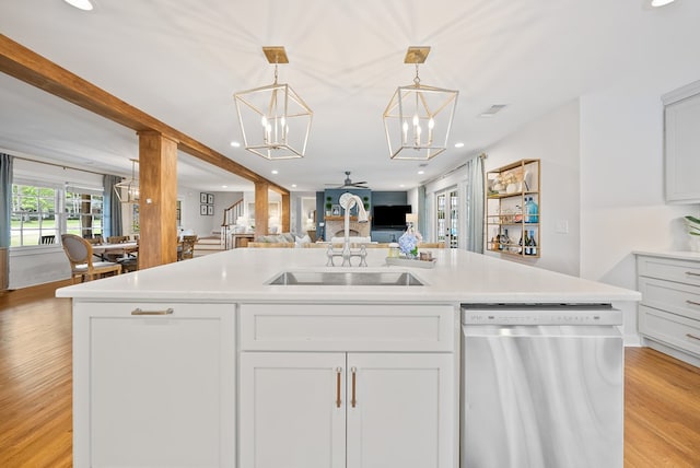 kitchen featuring dishwasher, open floor plan, a chandelier, light countertops, and a sink