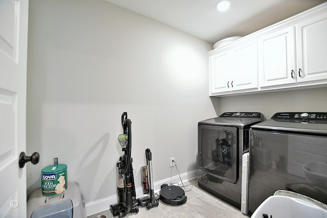 clothes washing area featuring cabinets, washing machine and dryer, and light tile patterned flooring