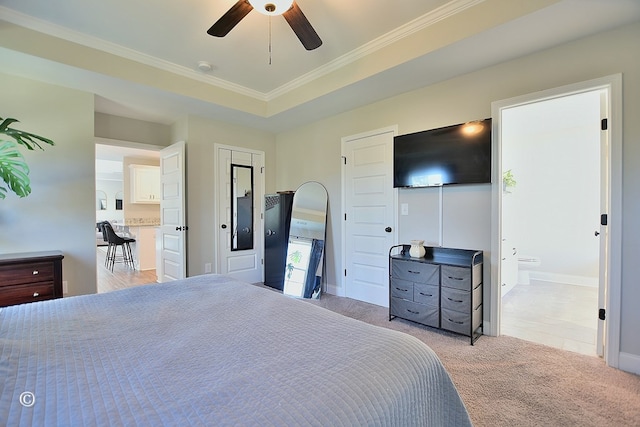 bedroom with ensuite bath, light carpet, ornamental molding, a raised ceiling, and ceiling fan