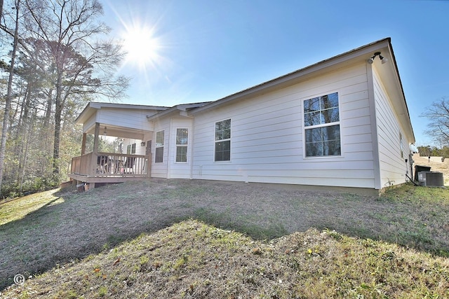 back of house featuring a deck, a lawn, and central air condition unit