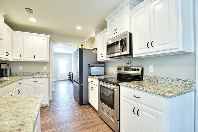 kitchen featuring light stone counters, white cabinets, dark hardwood / wood-style flooring, and stainless steel appliances