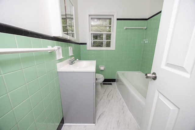 bathroom with vanity, tile walls, marble finish floor, a wainscoted wall, and toilet
