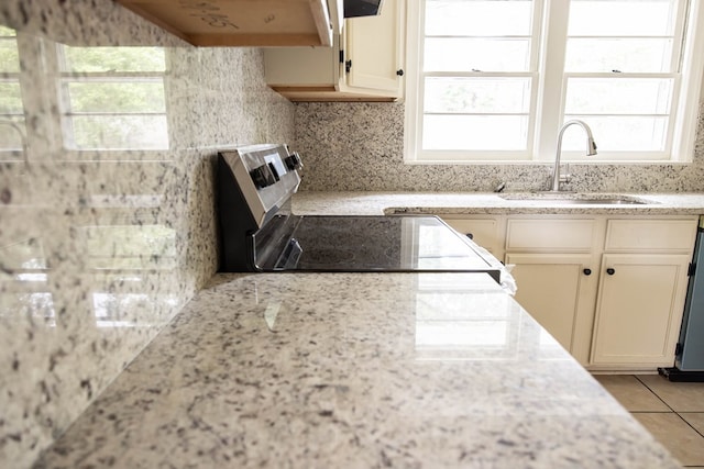 kitchen with light stone countertops, range with electric stovetop, a sink, and exhaust hood