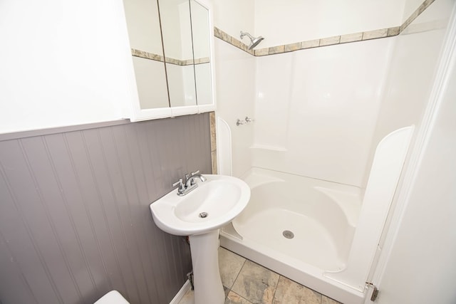bathroom featuring a wainscoted wall and a stall shower