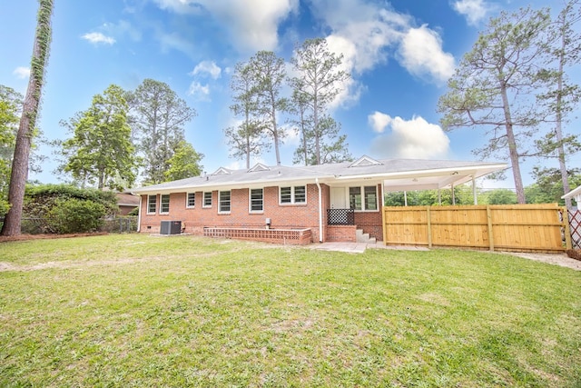 rear view of house featuring brick siding, central AC unit, fence, and a yard