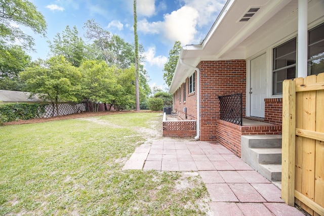 view of yard with fence, a patio area, and central AC unit