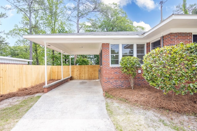 view of patio / terrace featuring fence, driveway, and an attached carport