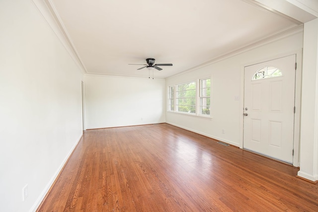 entryway featuring wood finished floors, ceiling fan, baseboards, ornamental molding, and visible vents