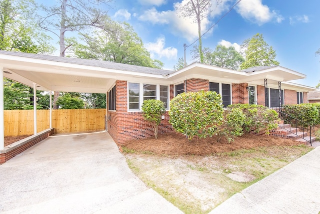 view of front of home featuring brick siding, driveway, fence, and an attached carport