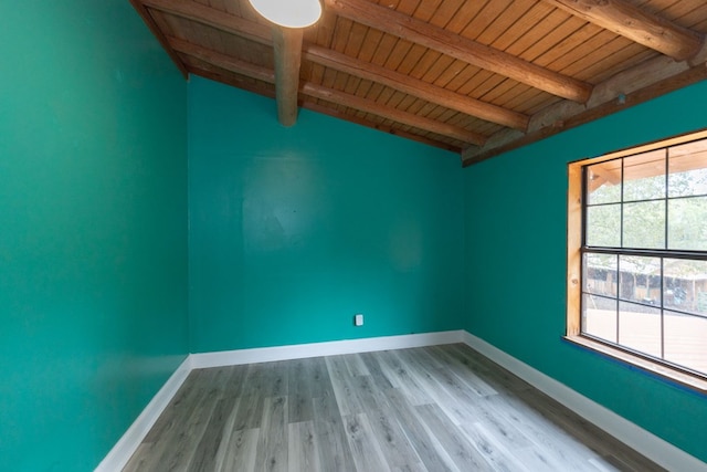 empty room featuring lofted ceiling with beams, wooden ceiling, and light hardwood / wood-style flooring