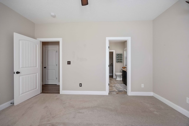 unfurnished bedroom featuring ensuite bath, ceiling fan, light colored carpet, and a textured ceiling