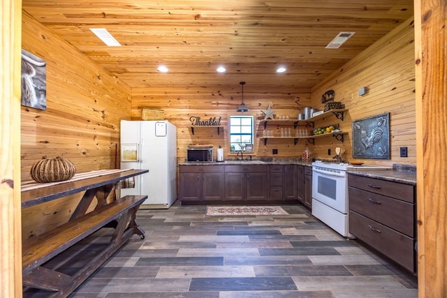 kitchen featuring white appliances, dark wood-type flooring, and wooden walls