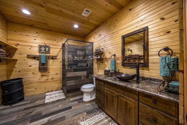 bathroom with walk in shower, vanity, wood-type flooring, toilet, and wood walls