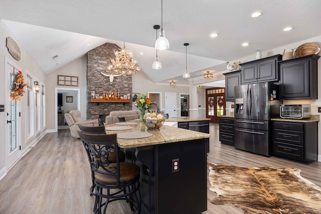 kitchen featuring pendant lighting, a breakfast bar, lofted ceiling, a center island with sink, and stainless steel appliances