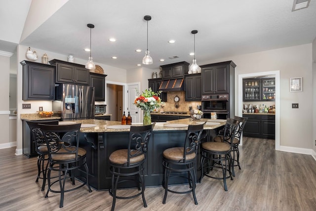 kitchen featuring stainless steel appliances, hanging light fixtures, a large island, and a breakfast bar area