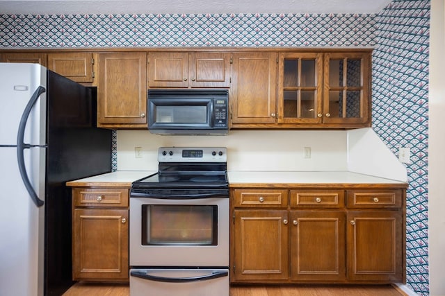 4608 Mayo Dr, Columbus, GA 31909 - kitchen with stainless steel appliances, light countertops, brown cabinetry, and glass insert cabinets