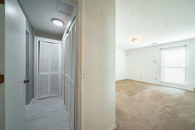 corridor featuring visible vents, baseboards, marble finish floor, carpet, and a textured ceiling