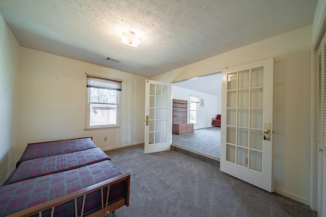 bedroom with visible vents, baseboards, carpet, a textured ceiling, and french doors