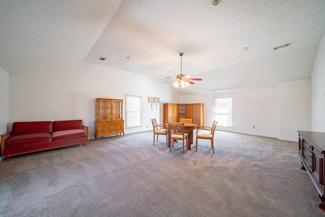 dining area featuring lofted ceiling, carpet flooring, and a textured ceiling