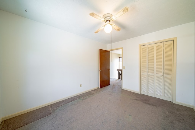 unfurnished bedroom with a ceiling fan, a closet, carpet flooring, and baseboards