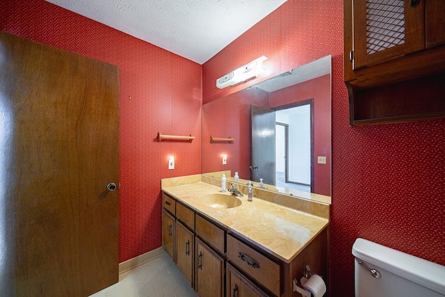 bathroom featuring a textured ceiling, toilet, vanity, baseboards, and tile patterned floors