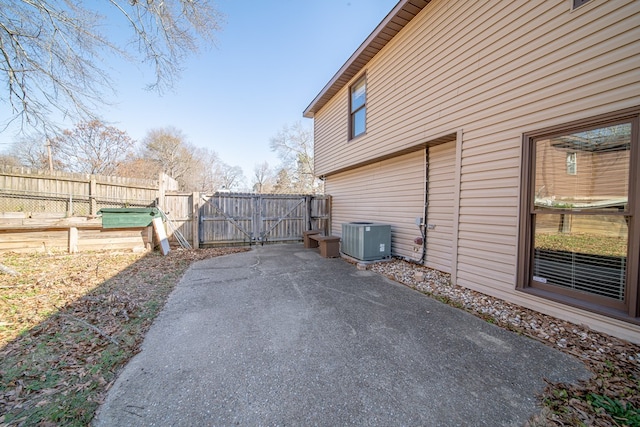 view of side of home featuring a gate, fence, and central air condition unit