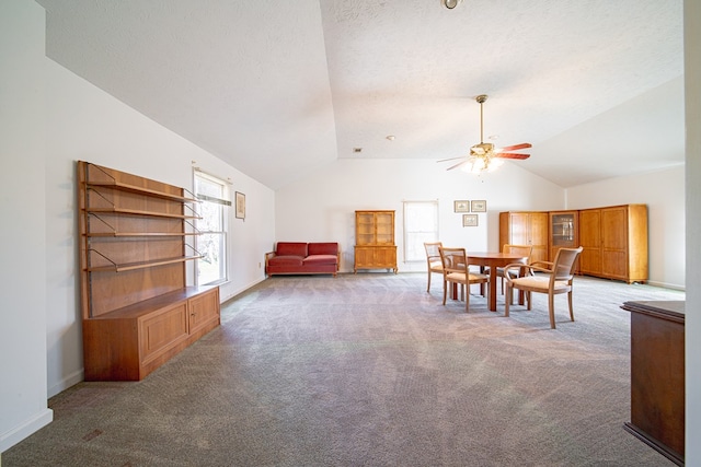 carpeted dining room with vaulted ceiling, a textured ceiling, a ceiling fan, and baseboards