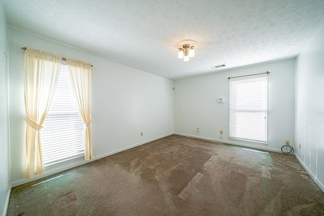 carpeted empty room featuring a textured ceiling, visible vents, and baseboards