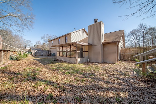 rear view of house with a gate, a chimney, fence, and a sunroom