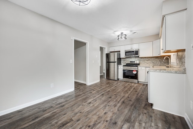 2245 Gennings Ct, Columbus, GA 31907 - kitchen featuring appliances with stainless steel finishes, dark wood-type flooring, decorative backsplash, white cabinets, and light stone countertops