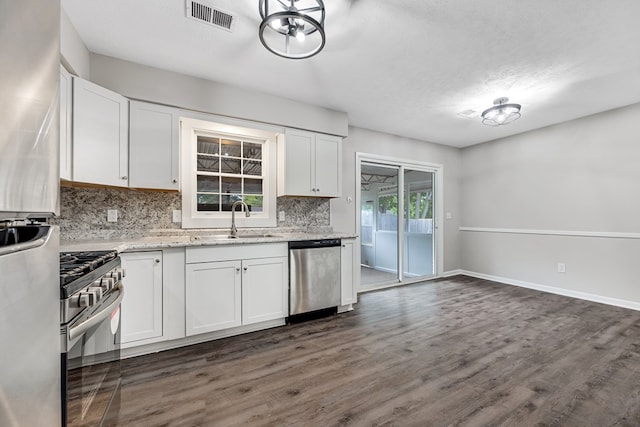 2245 Gennings Ct, Columbus, GA 31907 - kitchen featuring appliances with stainless steel finishes, tasteful backsplash, white cabinetry, dark wood finished floors, and light stone counters