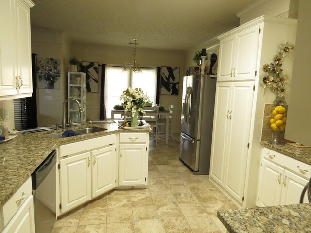 kitchen featuring white cabinets, a peninsula, a sink, stone counters, and appliances with stainless steel finishes