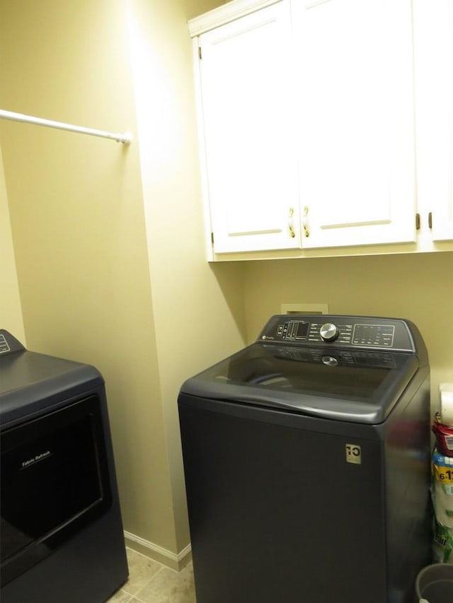 clothes washing area with cabinet space, baseboards, and washer / clothes dryer