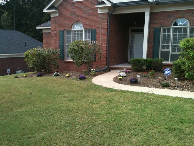 doorway to property with brick siding and a yard