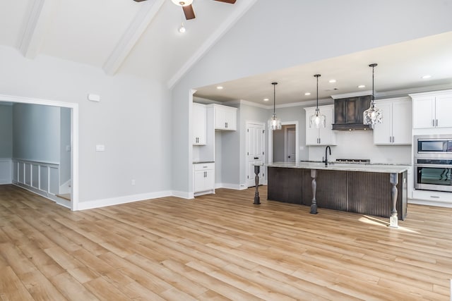 kitchen featuring a kitchen bar, white cabinetry, decorative light fixtures, stainless steel appliances, and a kitchen island with sink