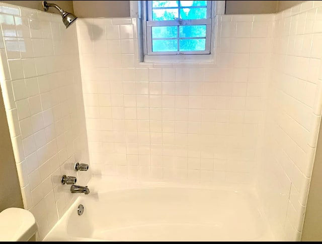 bathroom featuring toilet and tiled shower / bath