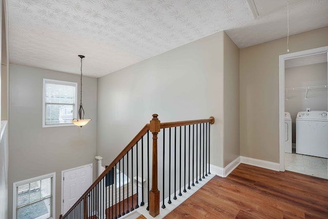 staircase with separate washer and dryer, wood-type flooring, and a textured ceiling