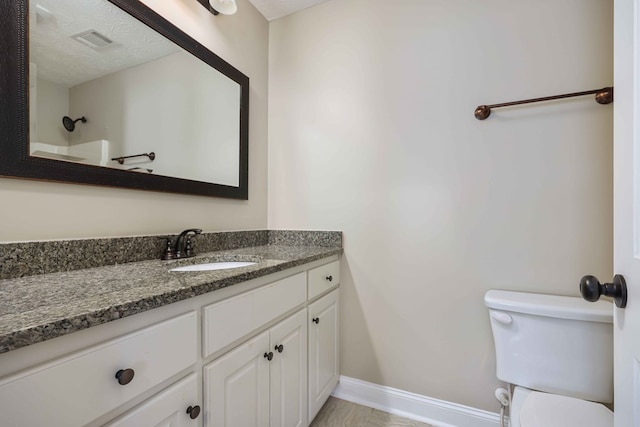 bathroom with vanity, toilet, and a textured ceiling