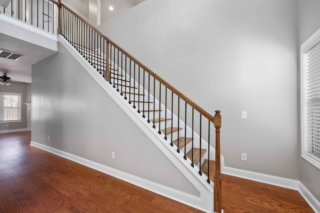 stairway featuring hardwood / wood-style flooring, ceiling fan, and a high ceiling