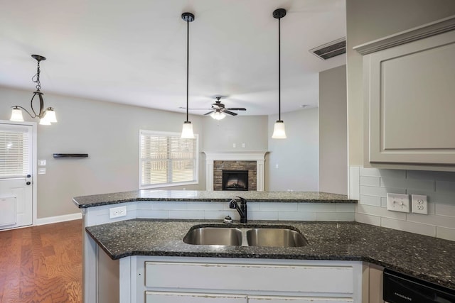 kitchen with sink, decorative light fixtures, dark hardwood / wood-style floors, and dark stone countertops