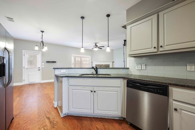 kitchen featuring hardwood / wood-style floors, ceiling fan with notable chandelier, sink, hanging light fixtures, and stainless steel appliances