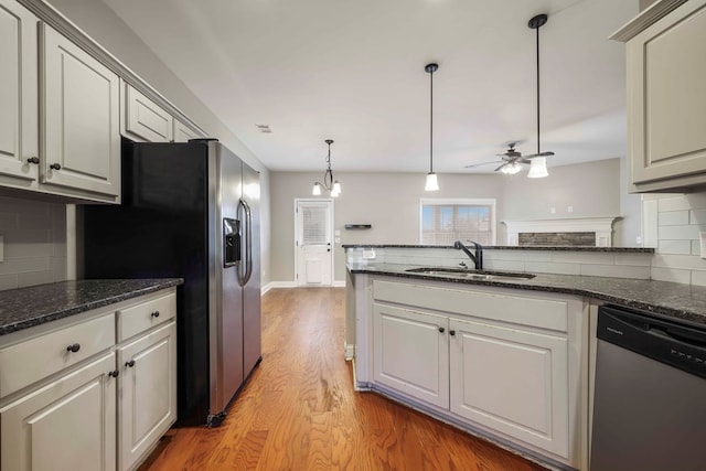 kitchen with sink, stainless steel appliances, backsplash, ceiling fan with notable chandelier, and light wood-type flooring